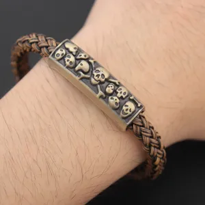 Detailed shot of men's punk braided leather bracelet featuring vintage skull metal plaque.