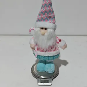 Vue détaillée de la figurine en peluche de gnome de Noël rose sur une balance de pesée.