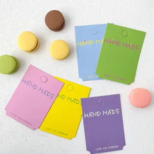 Gros plan de cartes en papier colorees pour pinces a cheveux faits main avec des macarons.