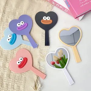 Detail view of cute heart-shaped hand mirrors with fun cartoon big mouth design for dorm use.