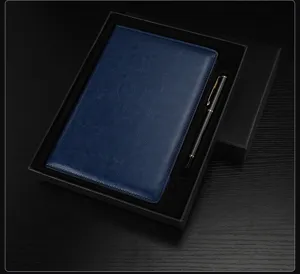 Primo piano del taccuino A5 in pelle blu e della penna in metallo in una confezione.