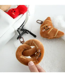 Close-up detail van schattige pluche brood en pretzel hangerbedels met lieve geborduurde gezichten.