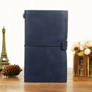 Gros plan detaille du carnet de voyage en cuir bleu fonce avec bande elastique et design portable.