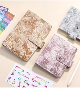 Vista dettagliata di quaderni con fogli mobili in jacquard cinese con adesivi e penna in vari colori.