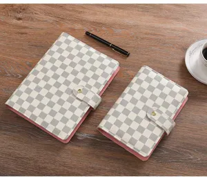 Detalle en primer plano de la elegante libreta de anillas con diseño de cuadros blanco y gris.