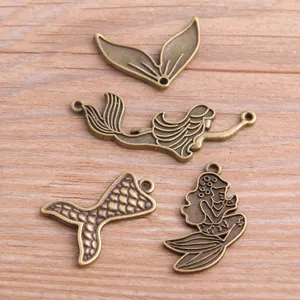 Detalle de primeros planos de dijes mixtos de sirena y cola en bronce antiguo para manualidades.
