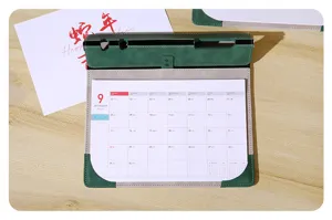Vista detallada del protector de escritorio de cuero verde con calendario mensual visible.