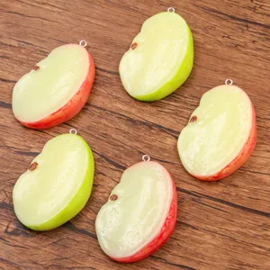 Gros plan détaillé de pendentifs en résine en forme de quartier de pomme avec anneau métallique.