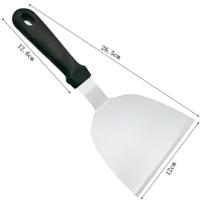 Stainless steel BBQ spatula detail, ergonomic black handle, wide metal blade for grilling.