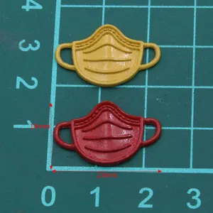 Vue détaillée de connecteurs de breloques de masques miniatures en métal jaune et rouge.