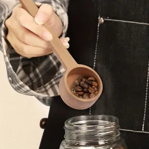 Splendido primo piano di un cucchiaio da caffè in legno che versa dei chicchi nel vaso.