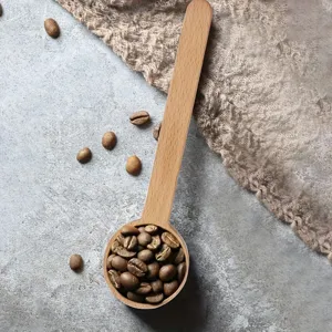 Vista di dettaglio del cucchiaio da caffè in legno con chicchi su sfondo strutturato.