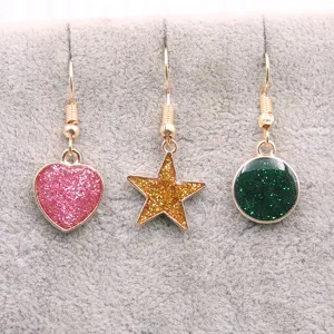 Détail des boucles d'oreilles en alliage doré avec pendentifs brillants cœur, étoile, rond.