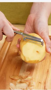Detalle de primer plano de pelador de acero inoxidable con cuchilla dentada para patatas.
