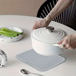 Silicone heat resistant mat detail showing non-slip ribbed texture on white table.