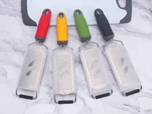 Detailed shot of four stainless steel graters with colorful handles and protective covers.
