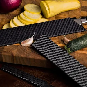 Close-up of black carbon fiber pattern knife sheaths protective covers on wooden cutting board.