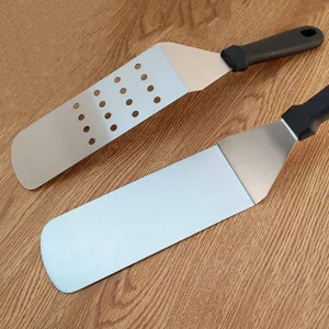 Stainless steel BBQ spatula detail, slotted and solid turners with ergonomic black handles.