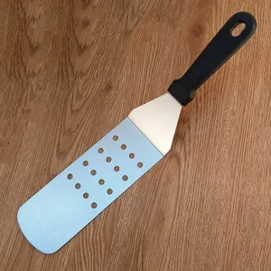 Stainless steel BBQ spatula detail, slotted turner with ergonomic handle for outdoor use.