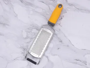 Stainless steel cheese grater with comfortable yellow handle for kitchen food prep.