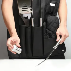 Detail shot of a black BBQ apron with stainless steel grill tools, spatula, and bottle.