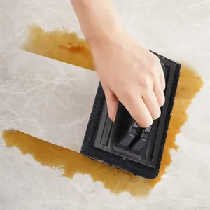 Detail shot of the black cleaning brush handle wiping stains, showing product usage and design.