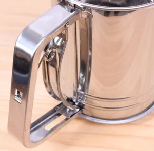 Primo piano del manico del setaccio per farina in acciaio inox, con dettagli della molla metallica.
