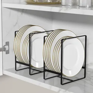 Close-up detail of black iron dish drying rack neatly organizing white and gold plates inside cabinet.