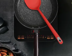 Close-up view of red silicone cooking spatula inside non-stick frying pan for kitchen use.