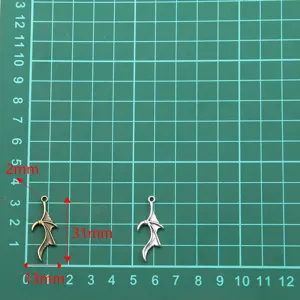 Detail shot of metal bat wing charms in two colors with size markers for DIY craft jewelry.