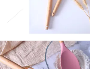 Silicone kitchen utensil detail showing wooden handle and heat resistant pink spatula head.