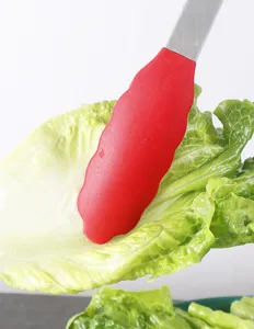 Stainless steel silicone food tong detail shot, red non-slip clamp holding fresh lettuce.