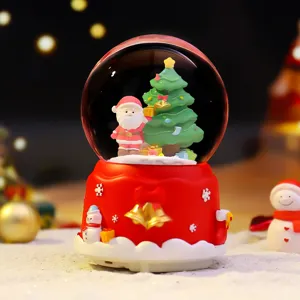 Close-up van kerstsneeuwbol met de Kerstman en boom, feestelijke bureaudecoratie detail.