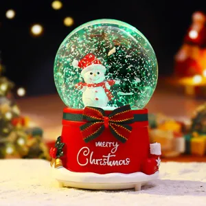 Christmas snow globe detail view showing the adorable snowman figurine and festive red bow base.