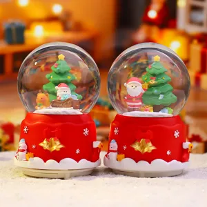 Kerst sneeuwbol muziekdoos met rode sokkel en feestelijke figuren als cadeau.
