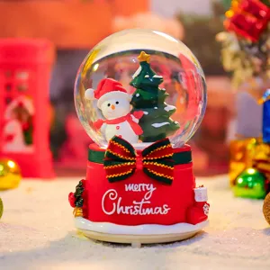 Close-up of Christmas snow globe detail, featuring cute snowman and tree inside base.