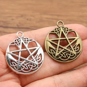 Primo piano di due ciondoli a pentagramma e mezzaluna con dettagli di nodi celtici.