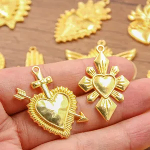 Close-up detail of vintage gold alloy sacred heart and arrow pendants for DIY jewelry making.