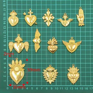 Detailed view of gold religious sacred heart charms, wings and vintage pendants for DIY crafts.