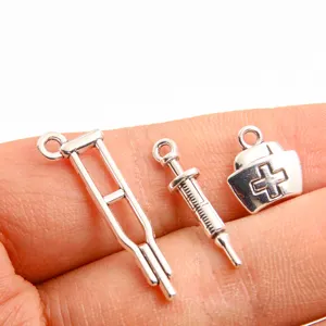 Close up view of medical theme DIY zinc alloy charms including crutch syringe and nurse hat.
