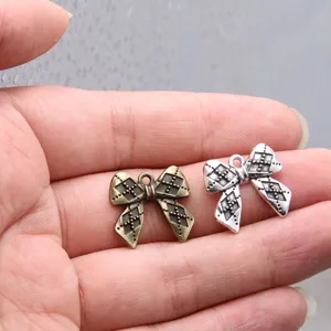 Close-up detail of vintage metal bow charms, bronze and silver DIY jewelry accessories.