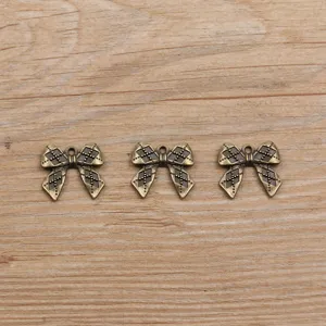 Detailed view of vintage bronze bow charms, perfect for DIY jewelry making and crafts.