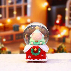 Jolie boule à neige de Noël avec ours rose et maison rouge pour décoration de fête chaleureuse.