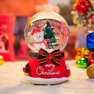 Close-up detail of Christmas snow globe featuring cute snowman and tree inside base.
