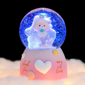 Nahaufnahme Detail der leuchtenden Schneekugel Spieldose mit süßer Puppe und Muschel-Dekor.