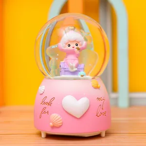 Detailansicht der niedlichen Unterwasserwelt Schneekugel Spieluhr, rosa Design mit Figur.