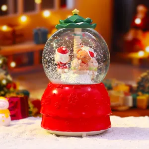 Nahaufnahme der festlichen Weihnachtsschneekugel mit niedlichen Figuren und stimmungsvollem Licht.
