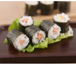 Vista dettagliata di involtini sushi fatti con lo stampo, disposti ordinatamente sul vassoio.