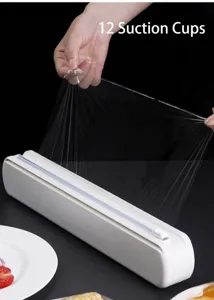 Dispensador compacto de film transparente con cortador deslizante y ventosas para cocina.