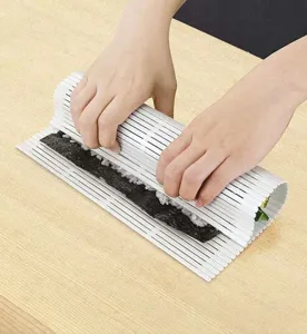 Primer plano de rollos de sushi con esterilla de plástico blanco en mesa de madera, cocina.